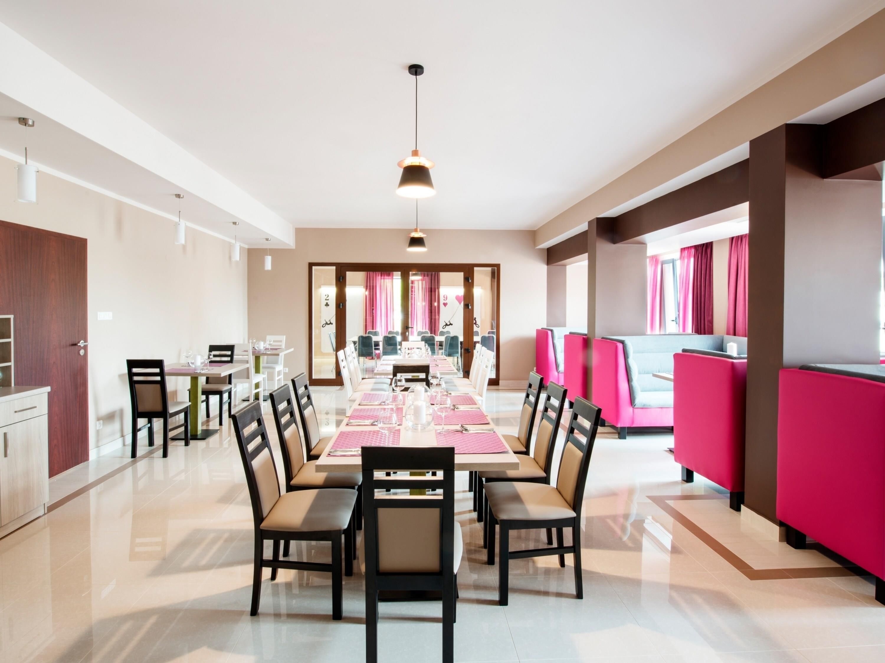 A spacious dining area with a long table, multiple chairs, and a bright pendant light.