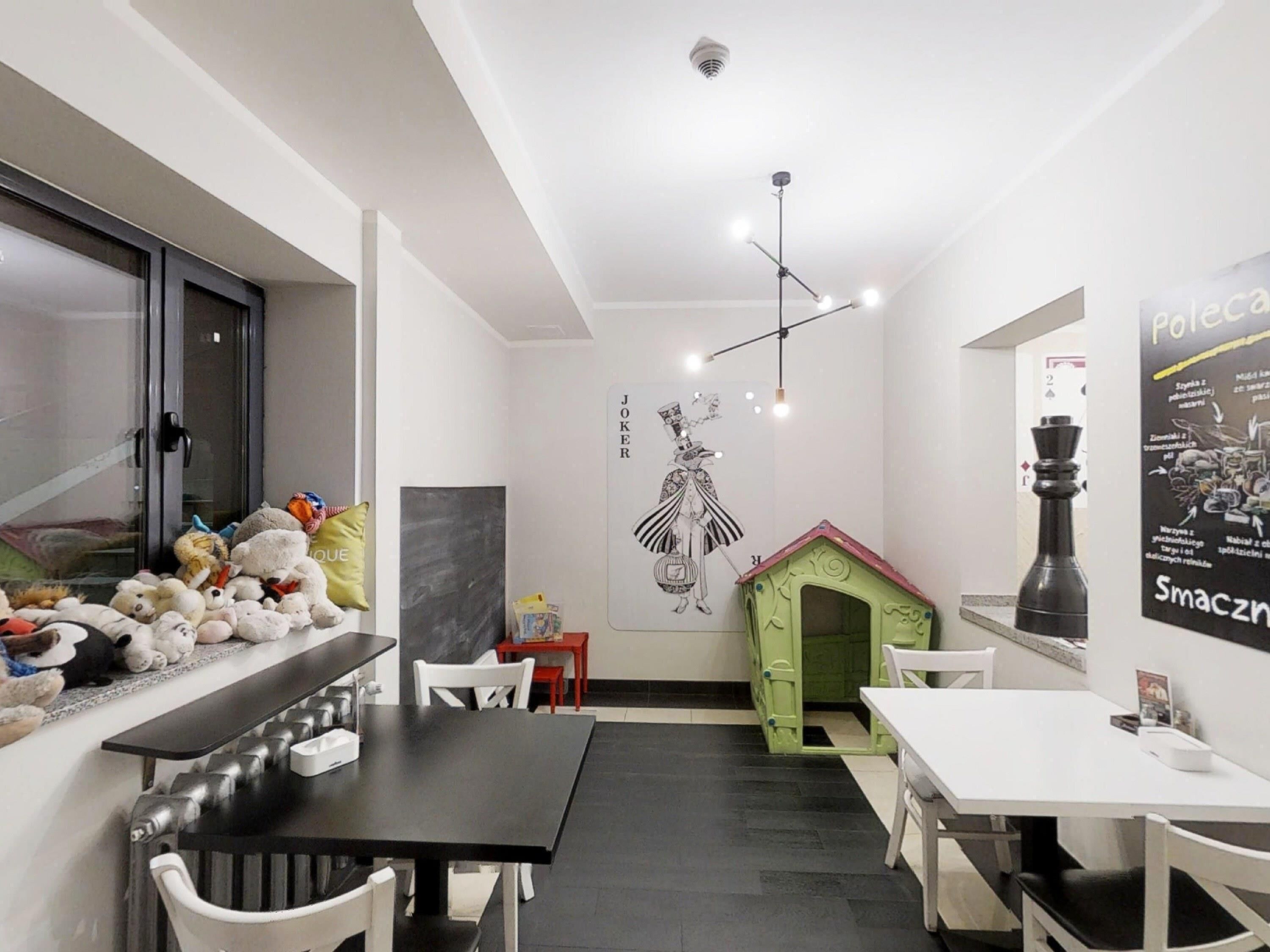A modern interior with a dining area, a playhouse, and a wall with a poster.
