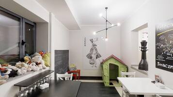 A modern interior with a dining area, a playhouse, and a wall with a poster.