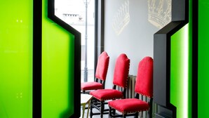 A modern interior with a green accent wall, a window with a view of buildings, and red upholstered chairs. - ibis Styles Gniezno Stare Miasto (Gniezno)