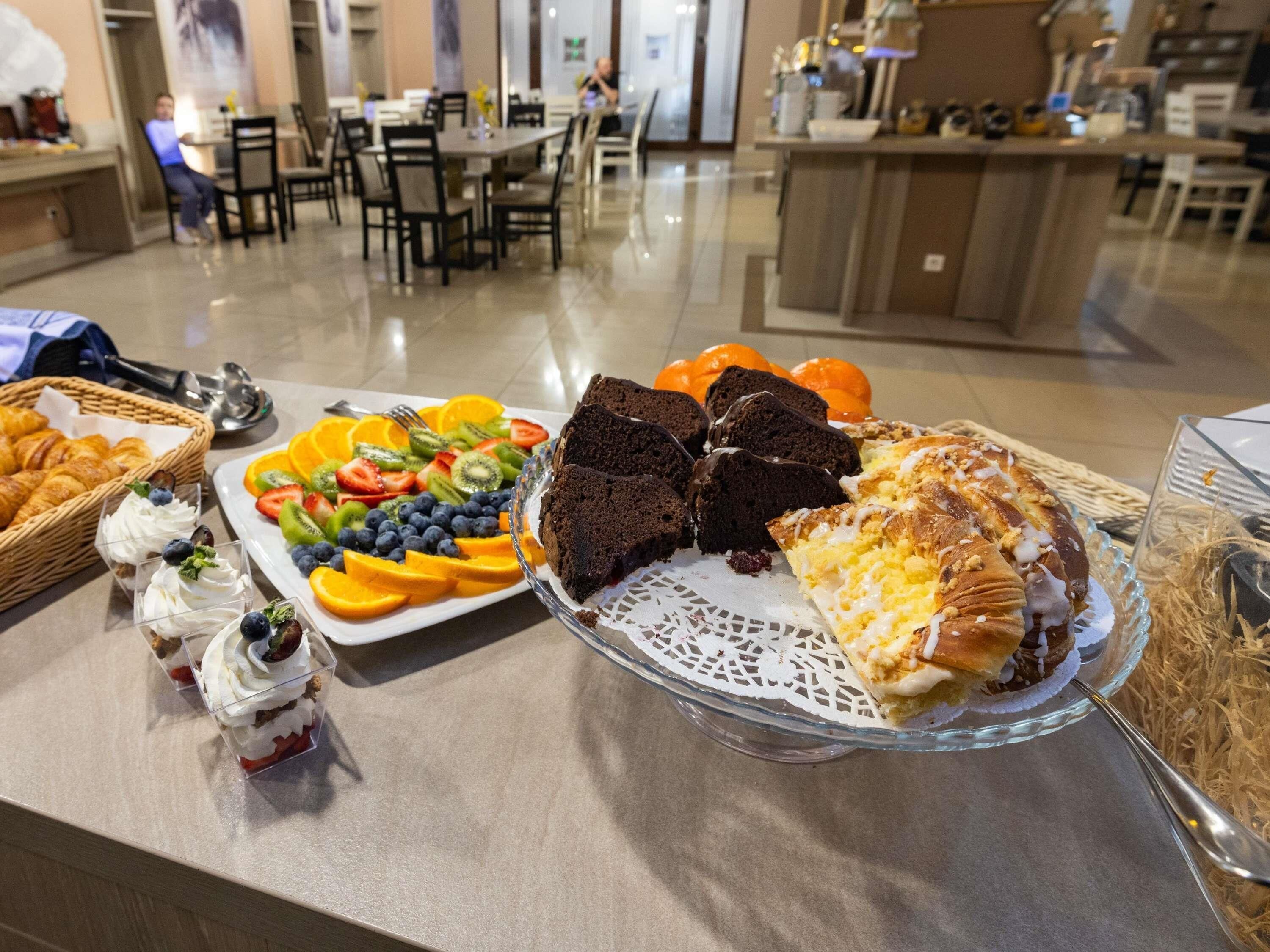 A buffet with various food items including pastries, fruits, and desserts.