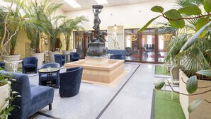 A lobby with a central fountain, seating area, and indoor plants. - ibis Styles Gniezno Stare Miasto (Gniezno)