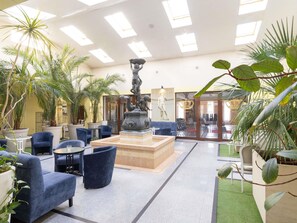 A lobby with a central fountain, seating area, and indoor plants. - ibis Styles Gniezno Stare Miasto (Gniezno)