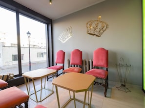 A room with four red upholstered chairs, a wooden table, and a decorative crown on the wall. - ibis Styles Gniezno Stare Miasto (Gniezno)
