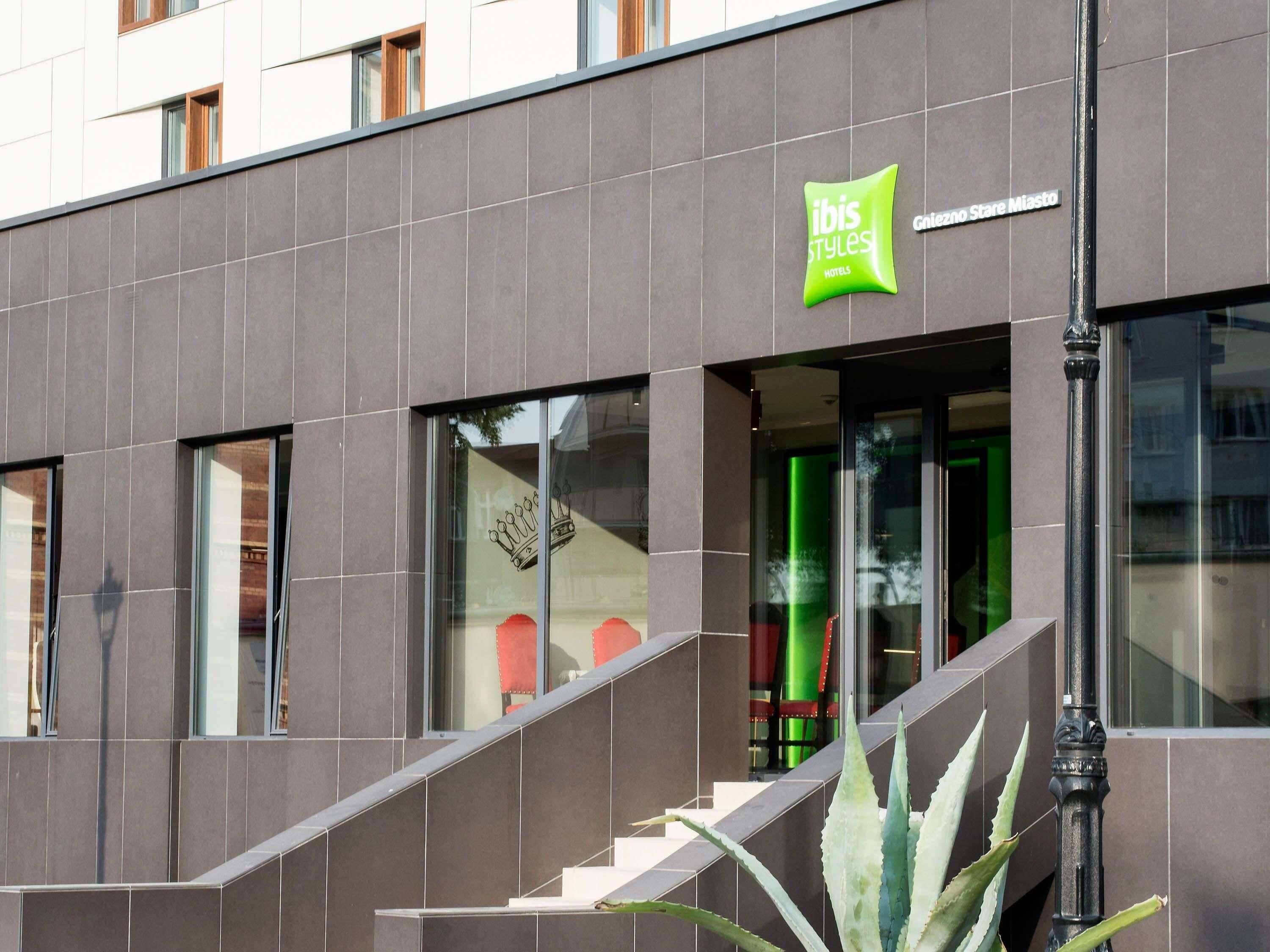 Fachada moderna de hotel com uma placa verde chamativa para 'ibis Styles Hotels'.