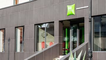 Fachada moderna de hotel com uma placa verde chamativa para 'ibis Styles Hotels'.