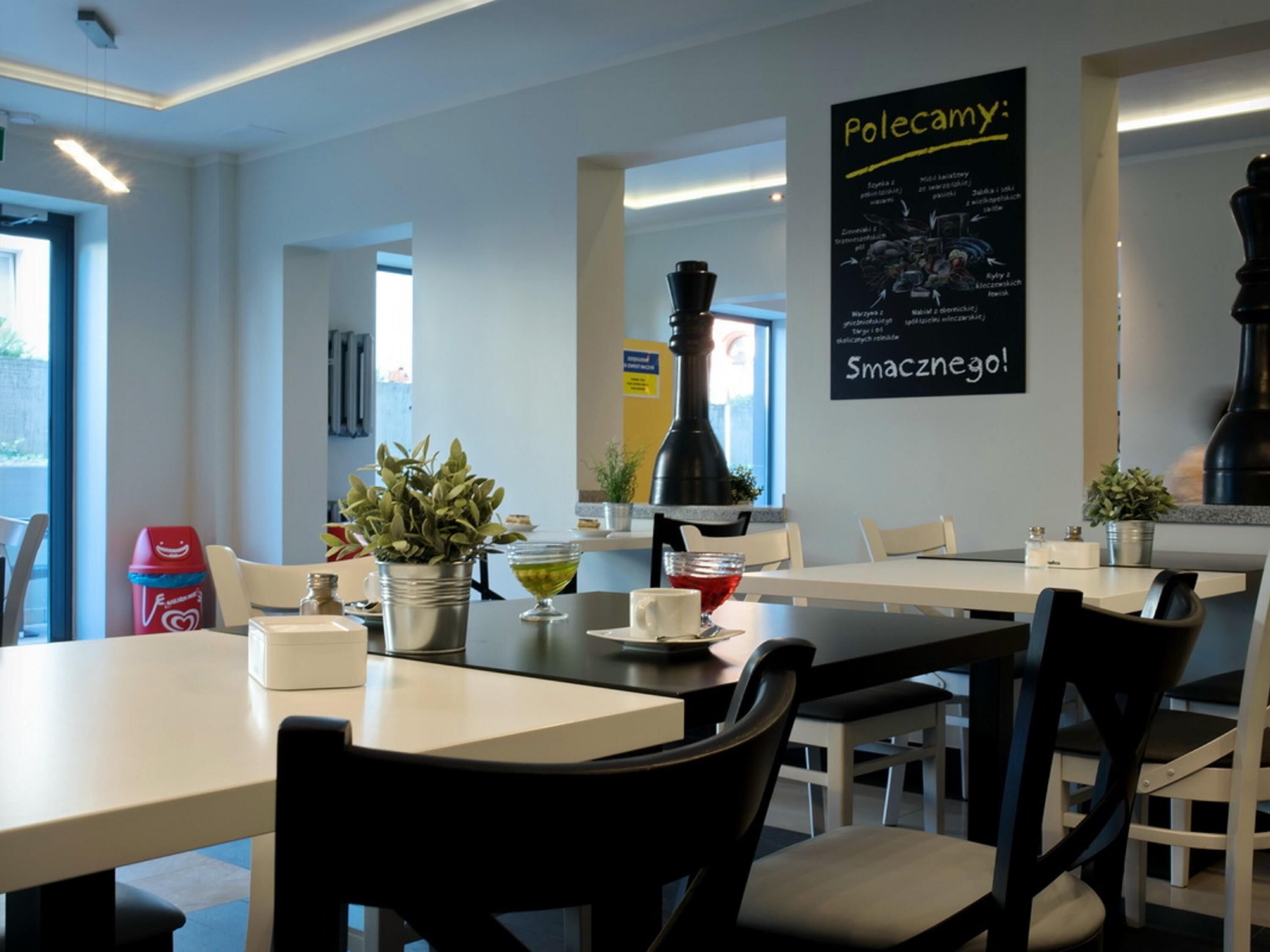 A modern dining area with tables, chairs, and a menu board.