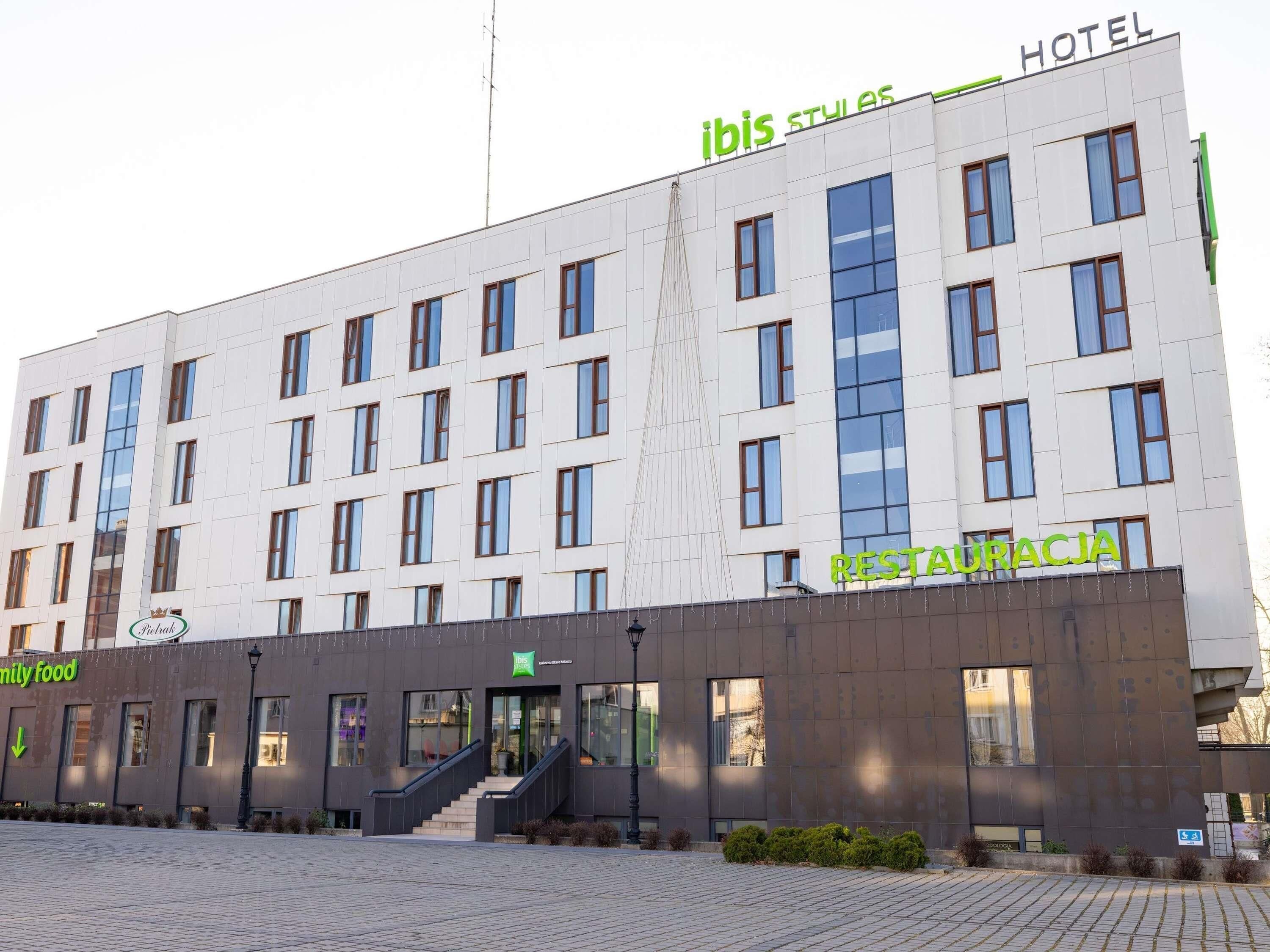 A hotel building with multiple floors, a staircase leading to the entrance, and a sign indicating a restaurant on the ground floor.