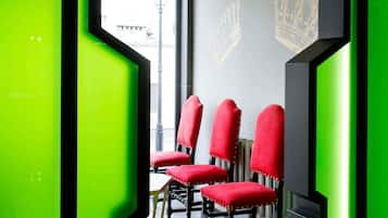 A room with a modern design, featuring a window with a view of the street, a radiator, and a wall with a crown emblem.