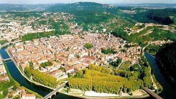 A panoramic view of a city with a river running through it, surrounded by greenery and residential areas.