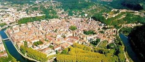 Una vista panorámica de una ciudad con un río que la atraviesa, rodeada de vegetación y zonas residenciales.