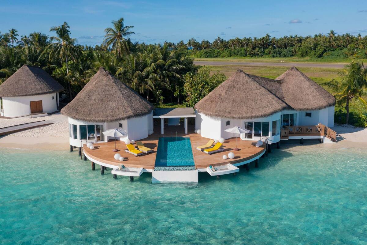 Un complexe hôtelier doté de bungalows sur pilotis, d’une piscine et d’une eau turquoise cristalline.