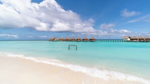 A beach with overwater bungalows and a swing set in the water. - Mercure Maldives Kooddoo Adult-Only Resort (Kooddoo)