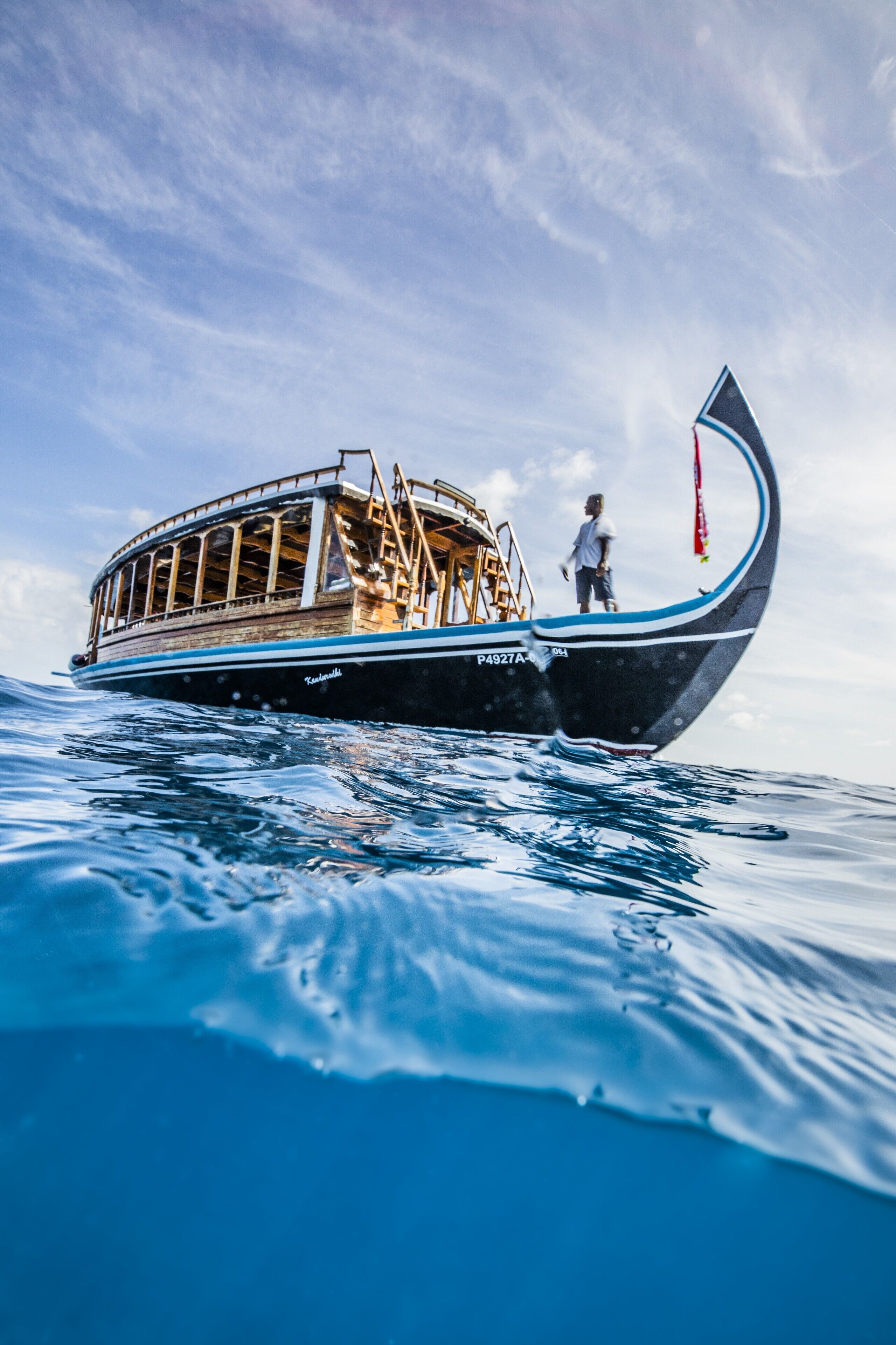 Un barco con proa curva, una persona de pie en la popa y una cabina con ventanas.