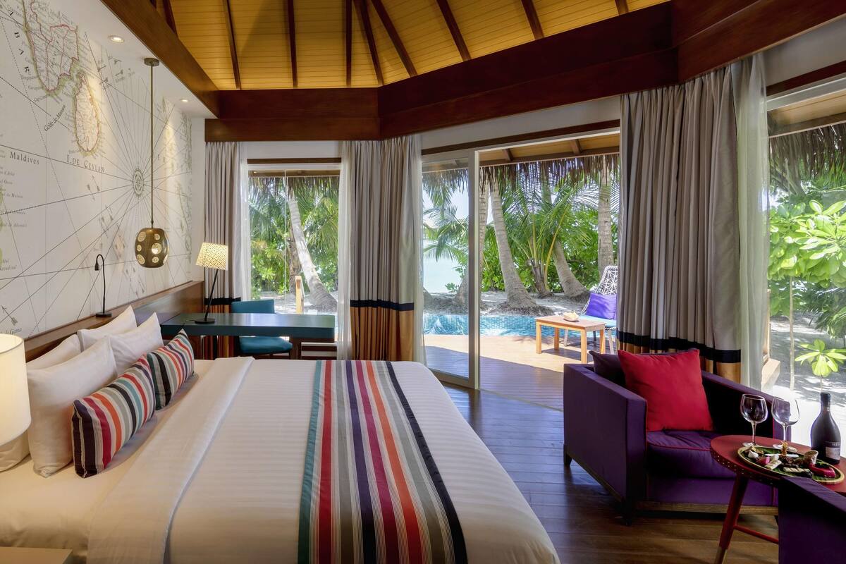 A spacious room with a large bed, a desk, and a seating area with a view of the ocean.