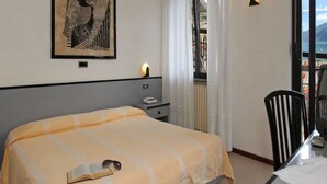 A hotel room with a bed, a nightstand, a chair, and a window with a view. - Europa (Limone sul Garda)