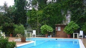 A rectangular swimming pool with a clear blue water surface, surrounded by potted plants and a brick wall. - Europa (Limone sul Garda)