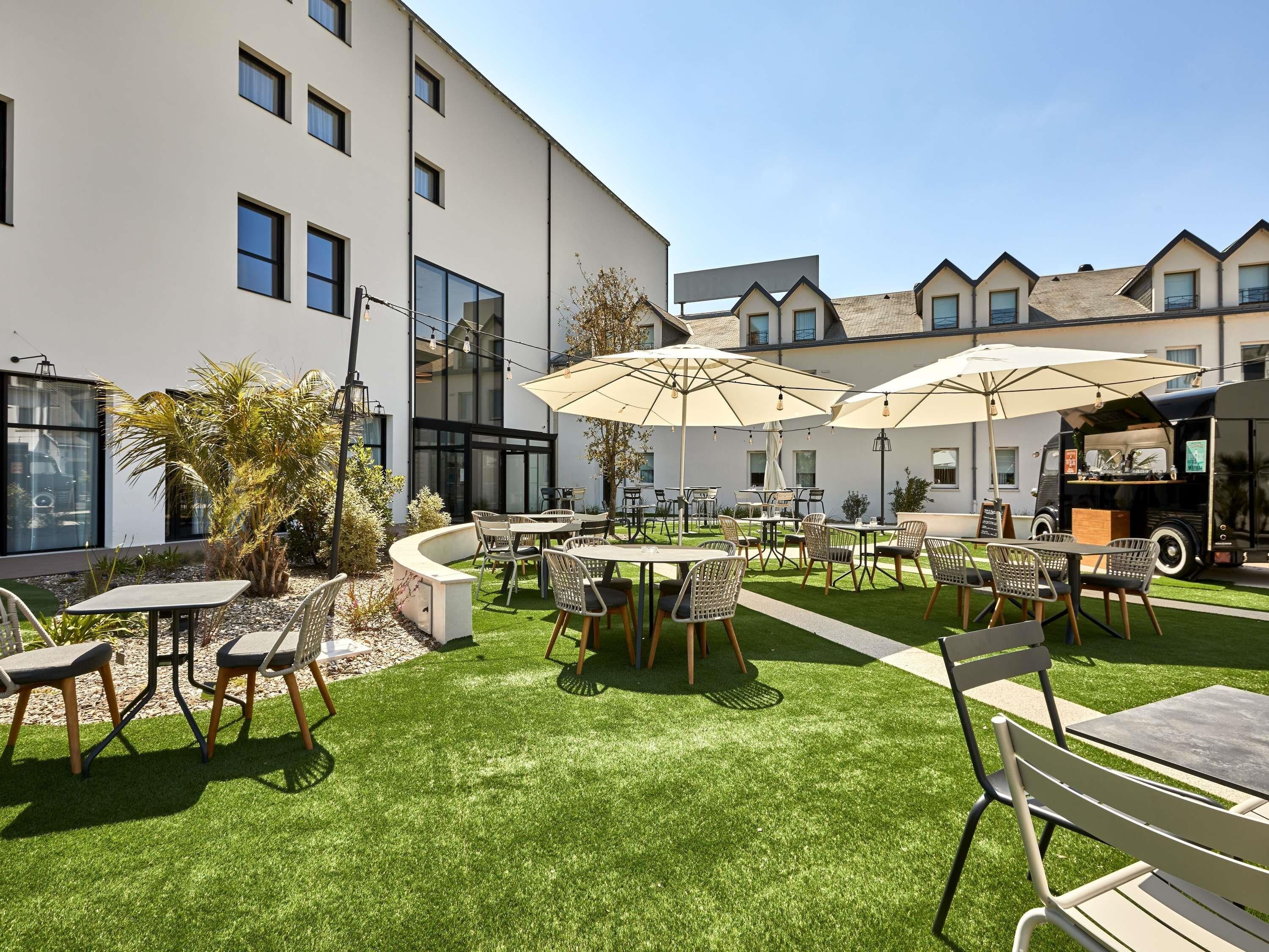 A courtyard with outdoor seating, tables, chairs, and umbrellas.