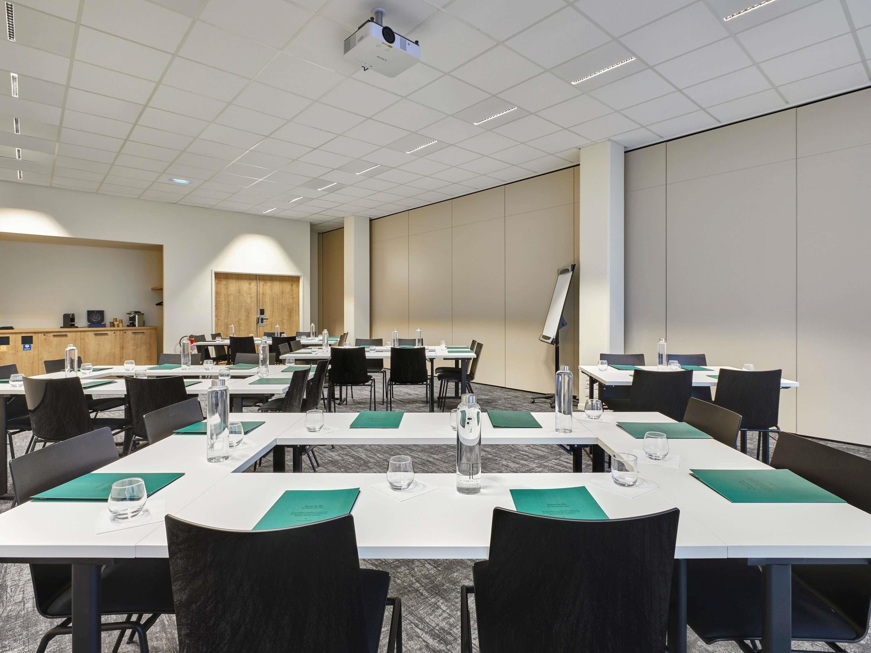 A conference room with multiple tables, chairs, a projector, and a whiteboard.