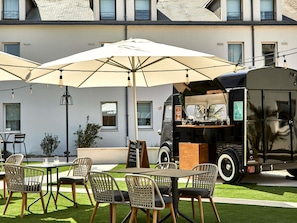 A food truck with a menu board, outdoor seating with chairs and tables, and a building in the background. - ibis Styles La Roche-sur-Yon (Mouilleron-le-Captif)