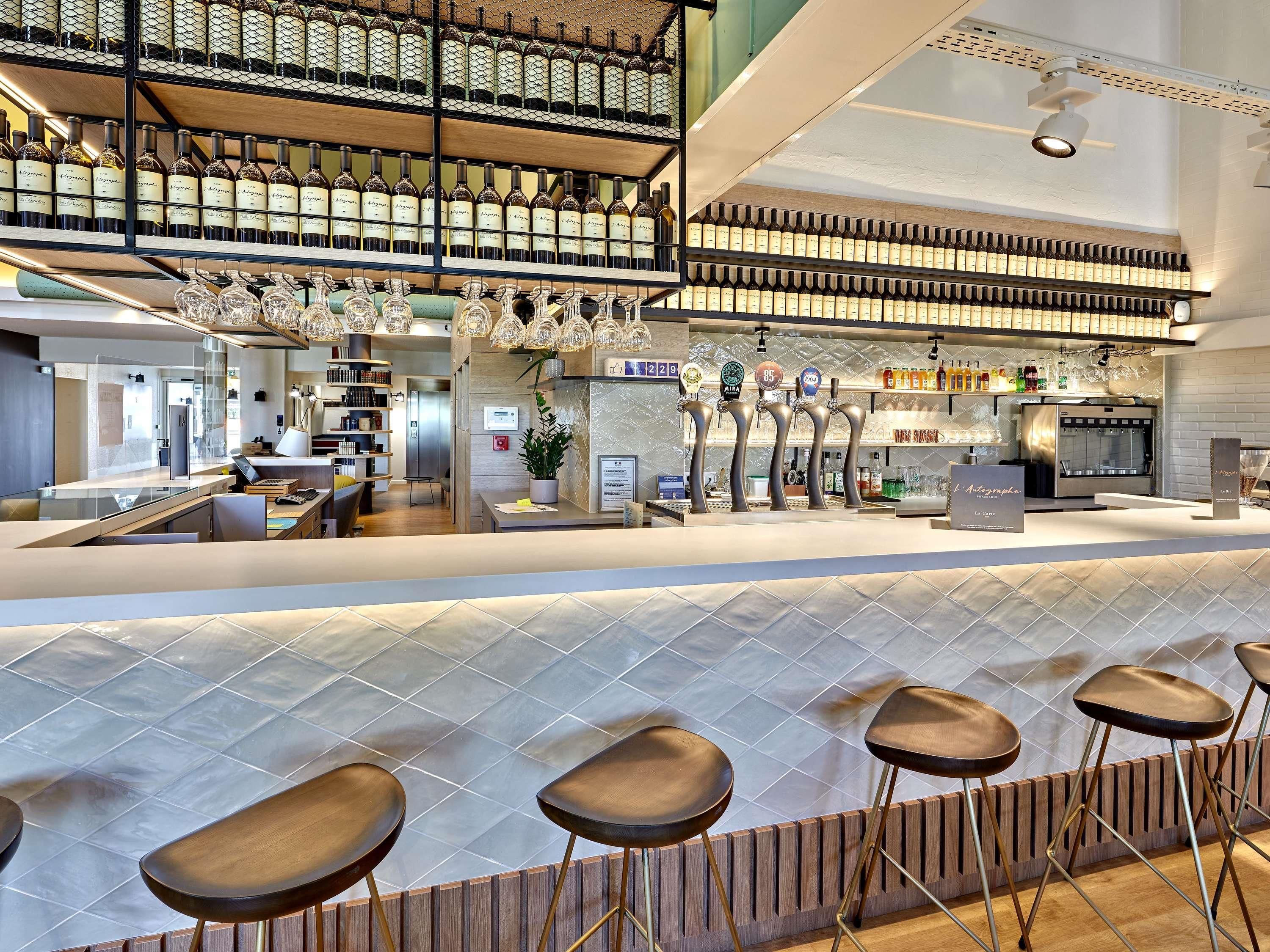 Un área de bar moderna con diversas opciones de asientos, una estantería para vinos y una cafetera.