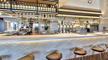 Un área de bar moderna con diversas opciones de asientos, una estantería para vinos y una cafetera.