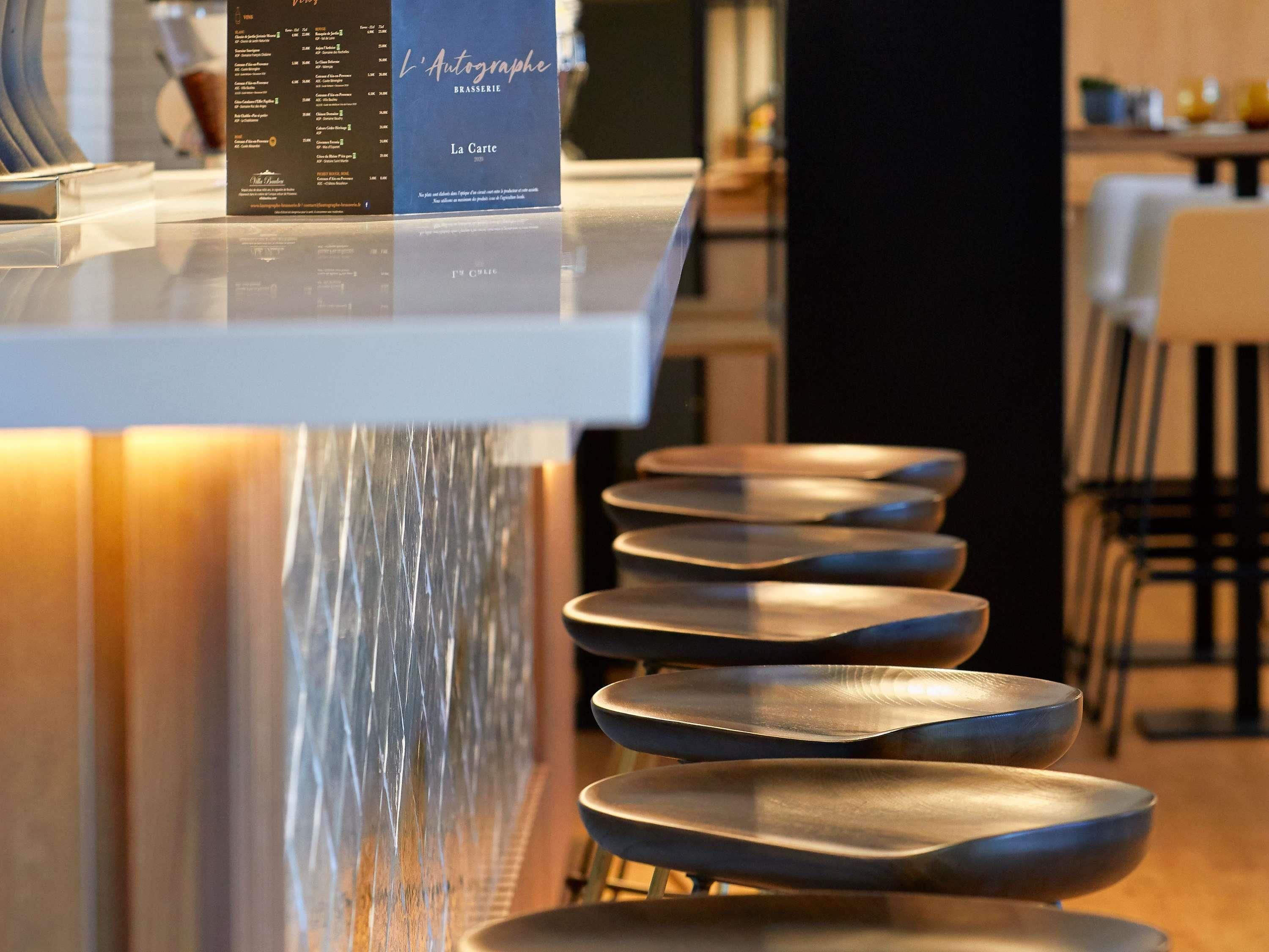 Un panneau affichant le menu de « L’Autographe Brasserie », avec une liste des plats et leurs prix.