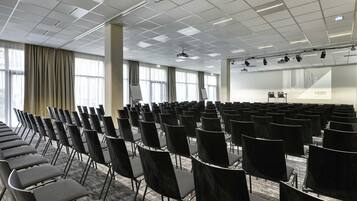 A conference room with rows of chairs, a projector, and a screen.