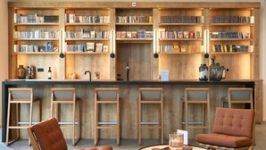 A modern library with wooden bookshelves, leather chairs, and a round table. - ibis Styles La Roche-sur-Yon (Mouilleron-le-Captif)