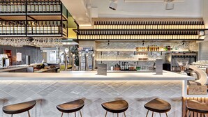 A bar area with a counter, stools, and shelves of bottles. - ibis Styles La Roche-sur-Yon (Mouilleron-le-Captif)
