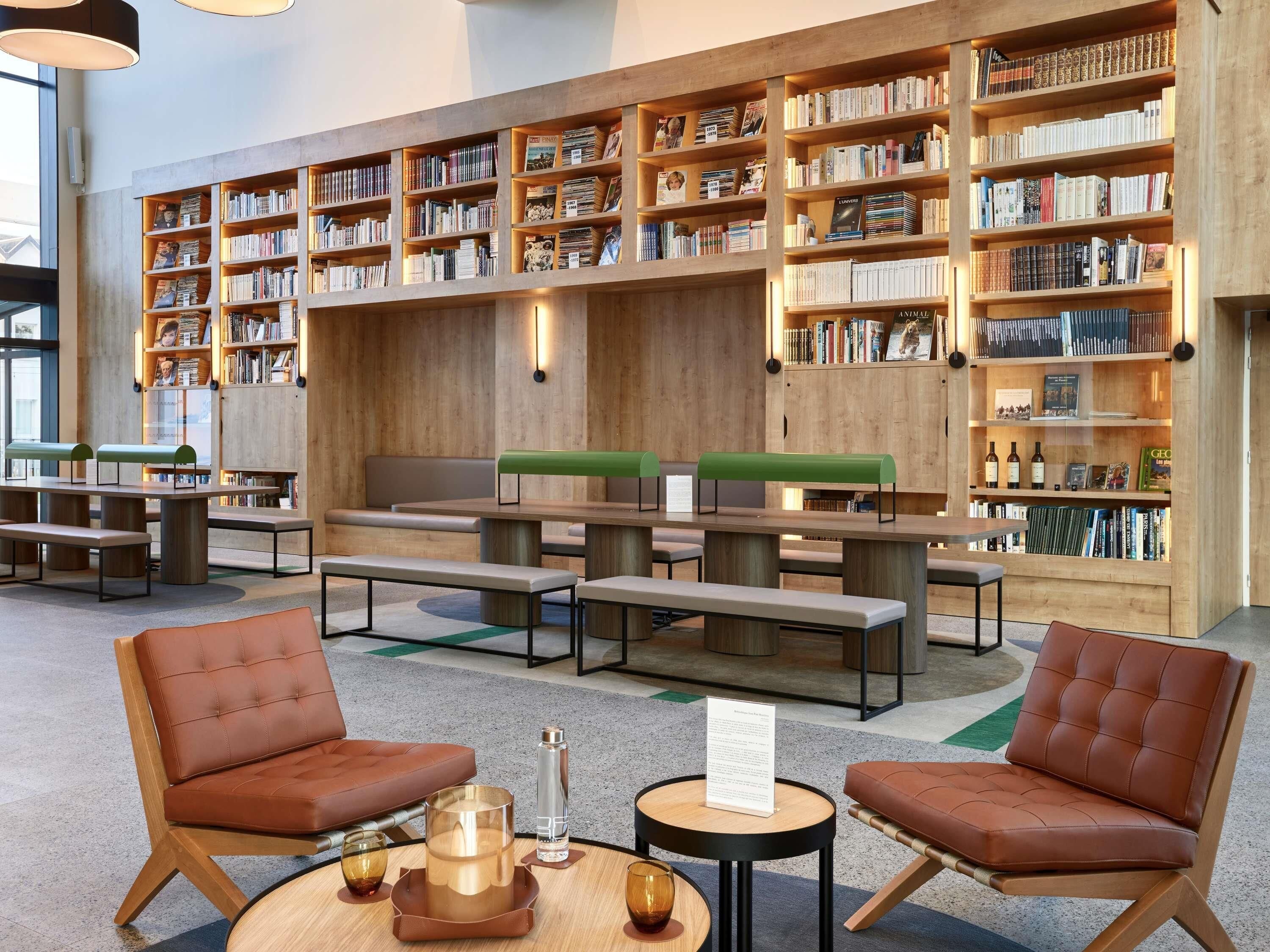 Una biblioteca moderna con estanterías, zonas de estar y mesas.