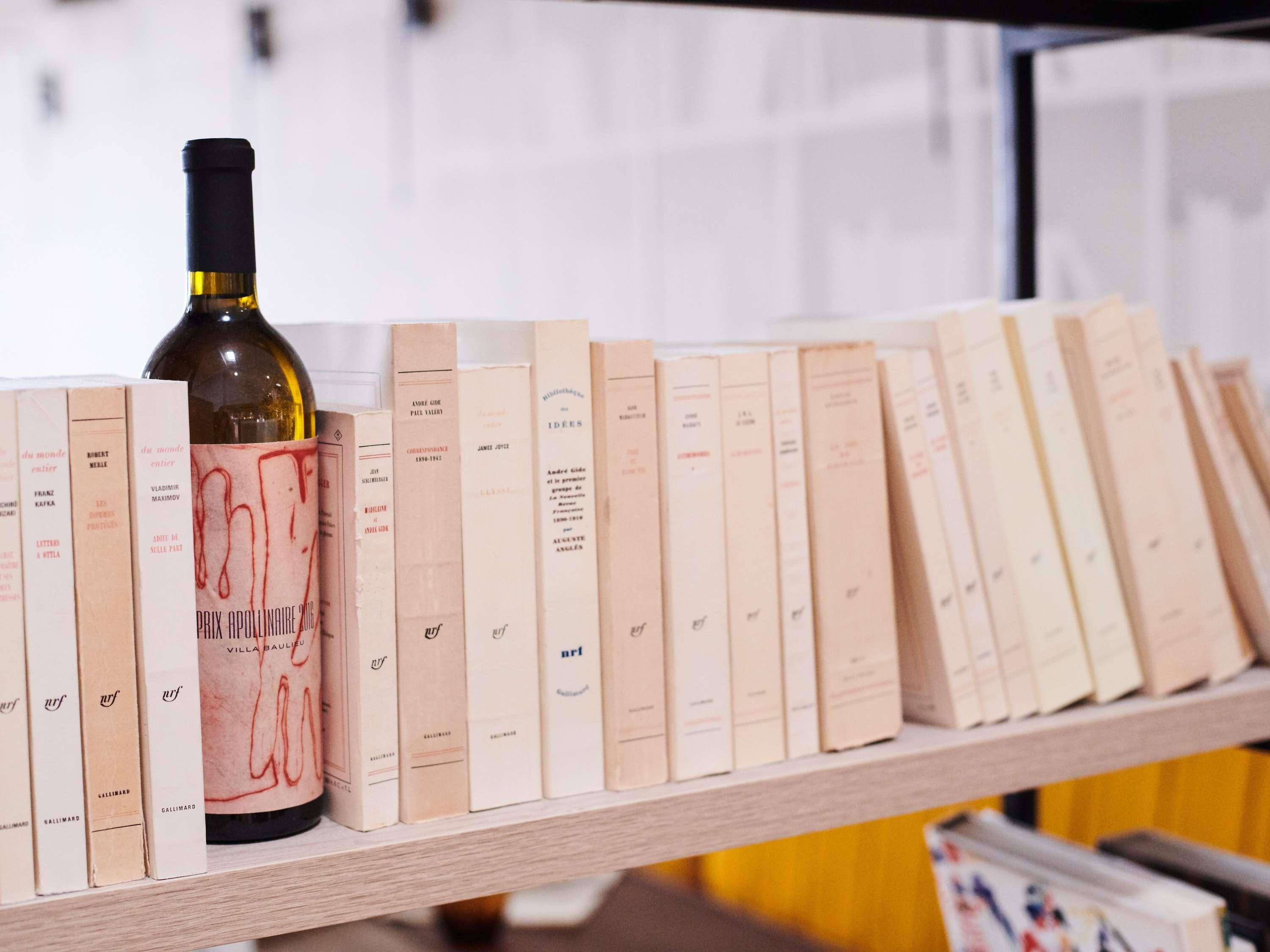 Una botella de vino y libros en una estantería.