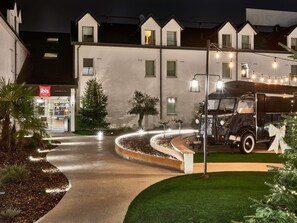 A hotel entrance with a Christmas tree, a vintage truck, and a well-lit pathway. - ibis Styles La Roche-sur-Yon (Mouilleron-le-Captif)