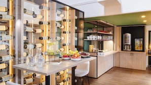 A modern kitchen with wine bottles on shelves, a fruit bowl, and a coffee machine. - ibis Styles La Roche-sur-Yon (Mouilleron-le-Captif)