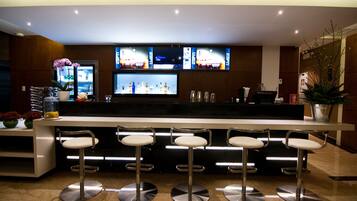 A bar area with three stools, a TV screen, and a bar counter.