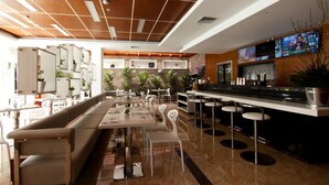A modern restaurant with a long counter, bar stools, and a variety of seating options including a bench and individual chairs. - LYZ Business Hotel (Lima)