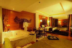 A hotel room with a large bathtub, a dining area, and a bed. - Royal Asnof Hotel (Pekanbaru)