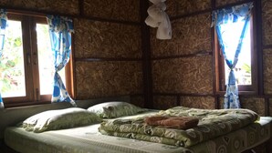 A room with a bed, wooden walls, and a window with curtains. - Family Huts (Pai)
