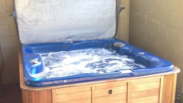 Un bain à remous en bois, avec un intérieur bleu, un couvercle blanc et une base en bois.