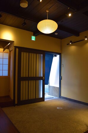 A hallway with a traditional sliding door, a ceiling light fixture, and an exit sign.