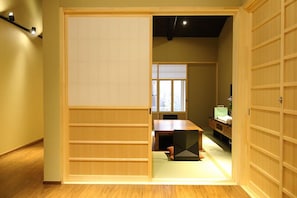 A traditional Japanese room with sliding doors, a tatami mat floor, a low table, and a futon bed.