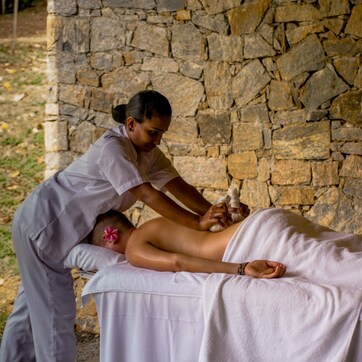 A massage therapy session in a stone-walled room with a massage table and a client.
