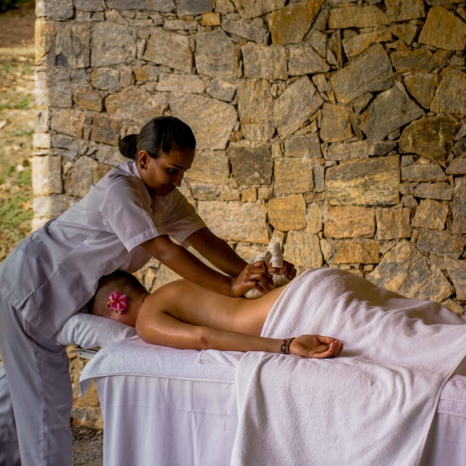 A massage therapy session in a stone-walled room with a massage table and a client.