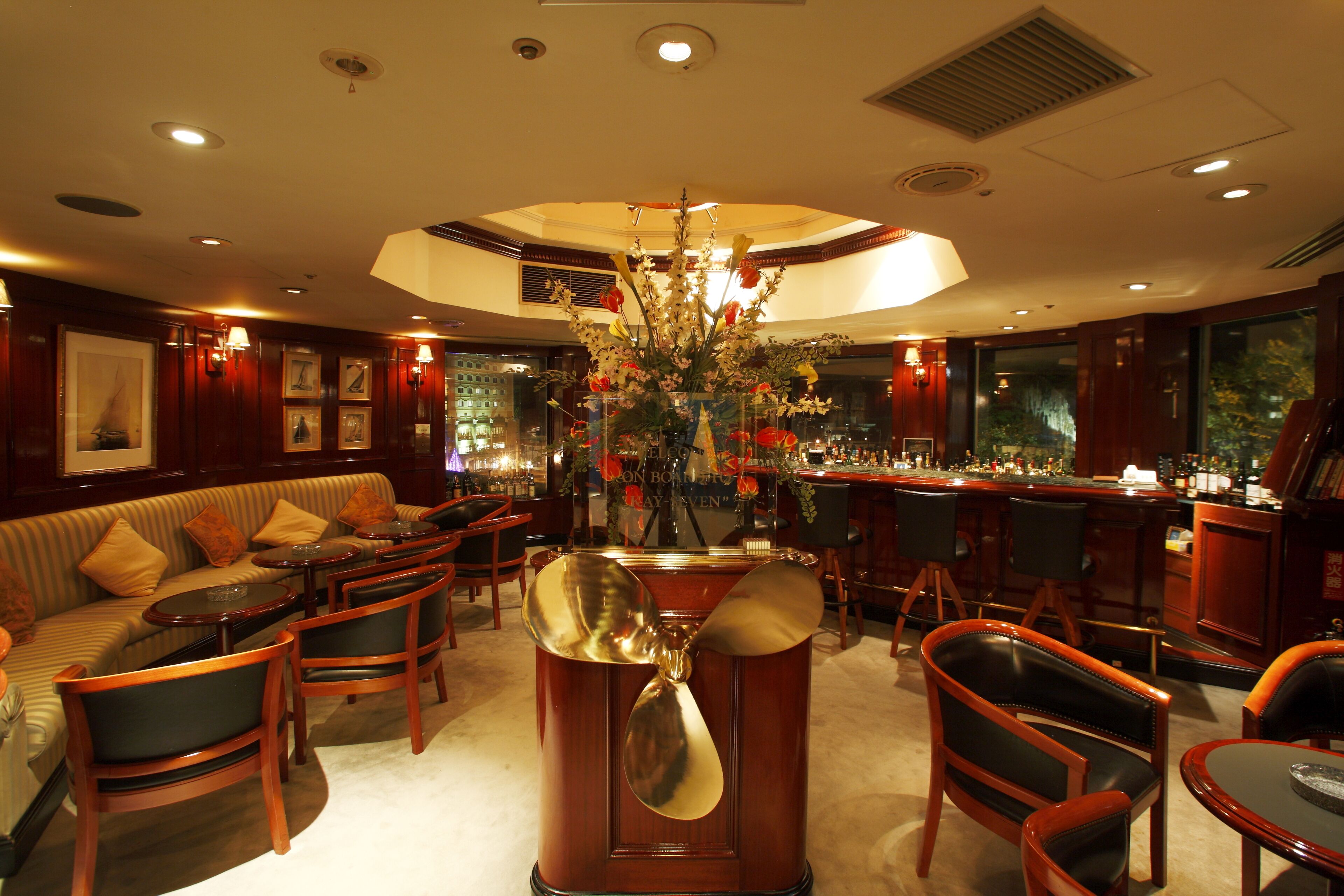 Una zona de bar con muebles de madera, un jarrón decorativo grande y cuadros en las paredes.