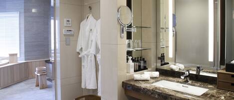A modern bathroom with a large mirror, a sink, and a shower area.