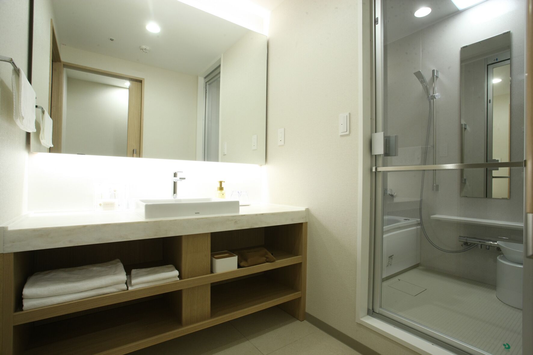 Un baño moderno con un espejo grande, un lavabo y una ducha con cerramiento de vidrio.