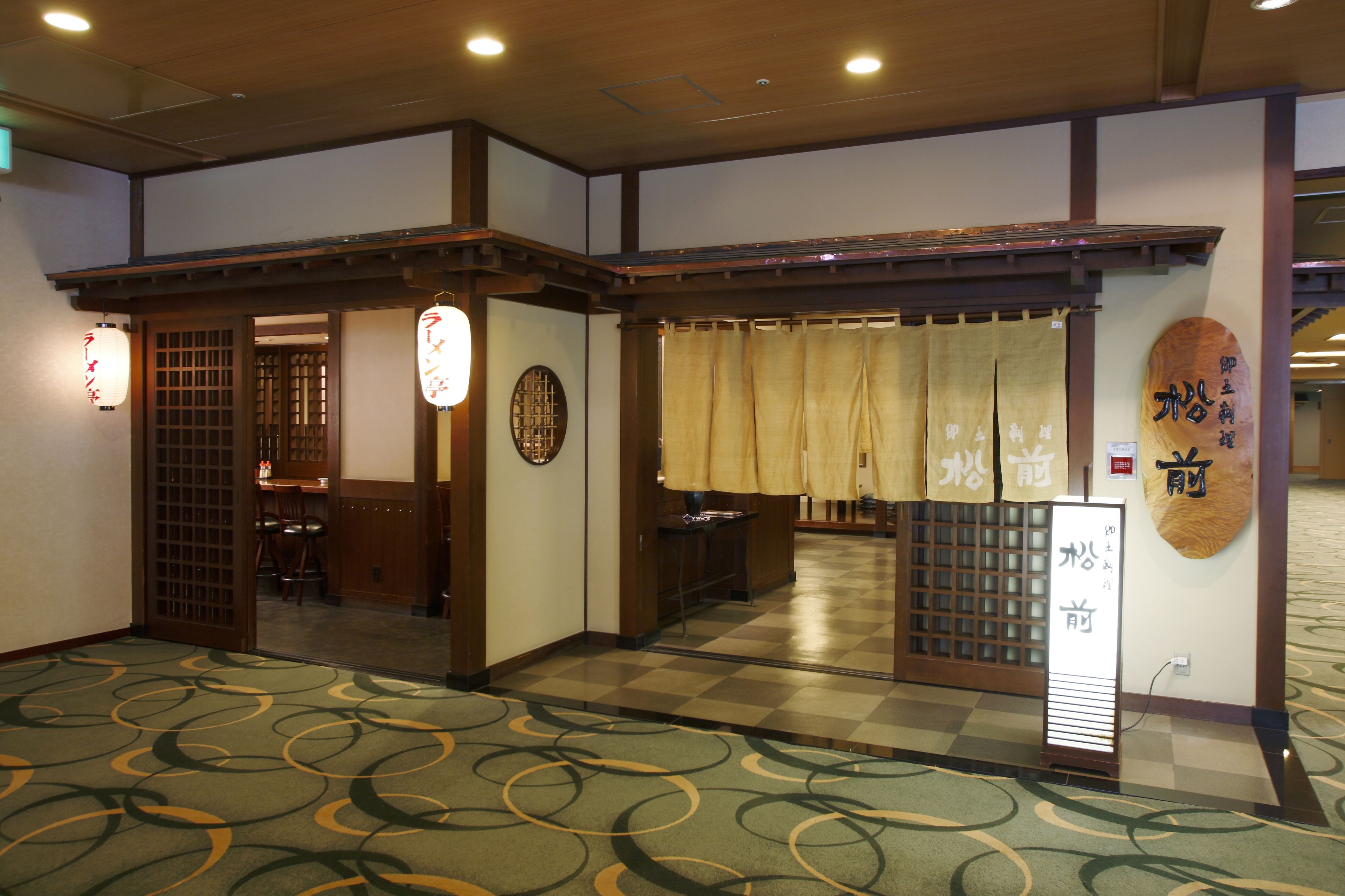 A traditional Japanese-style room with tatami flooring, a shoji screen entrance, and a reception desk with a wooden sign.