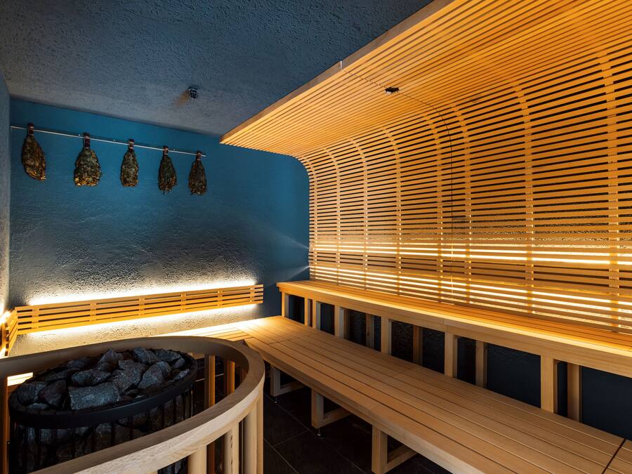 Una sauna con bancos de madera y un calentador fijado a la pared.