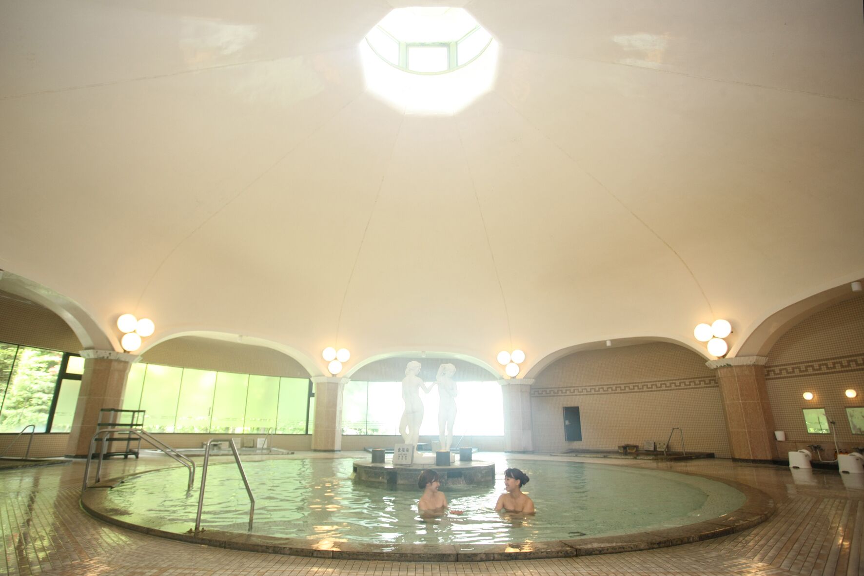 Una amplia piscina interior con techos abovedados y múltiples luminarias.