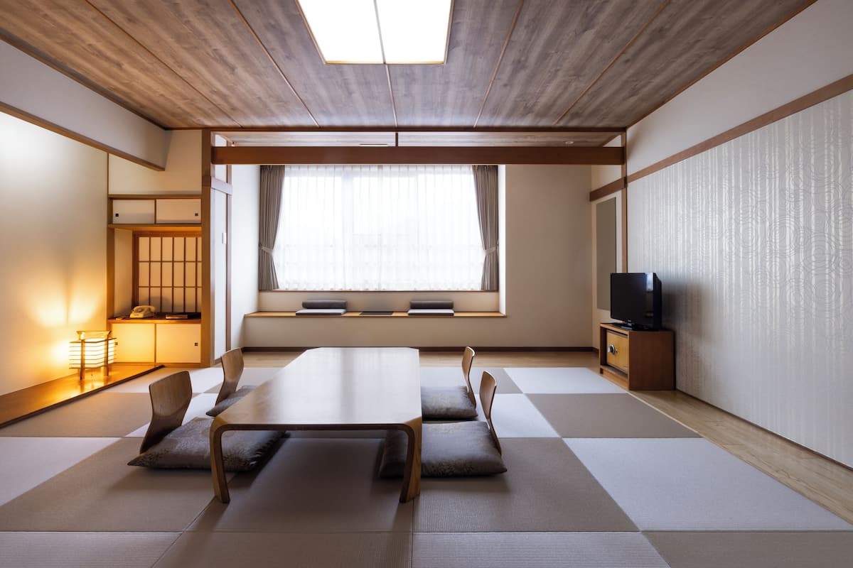 A traditional Japanese room with tatami flooring, a low table, and a television.